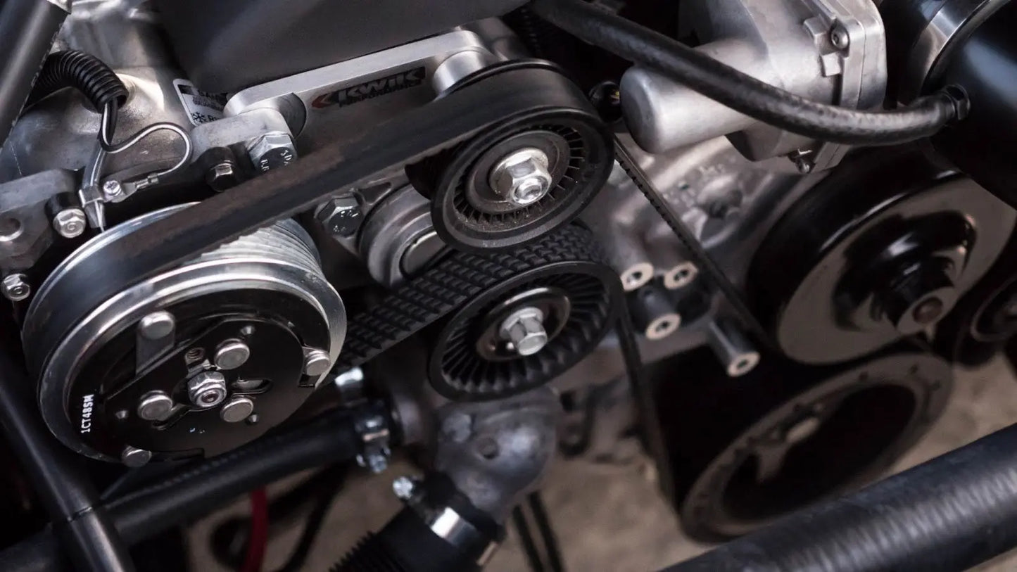Serpentine belt wrapping around different pulleys on an engine.