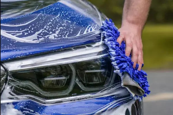 
              Man using blue car sponge to apply soap to a blue car.