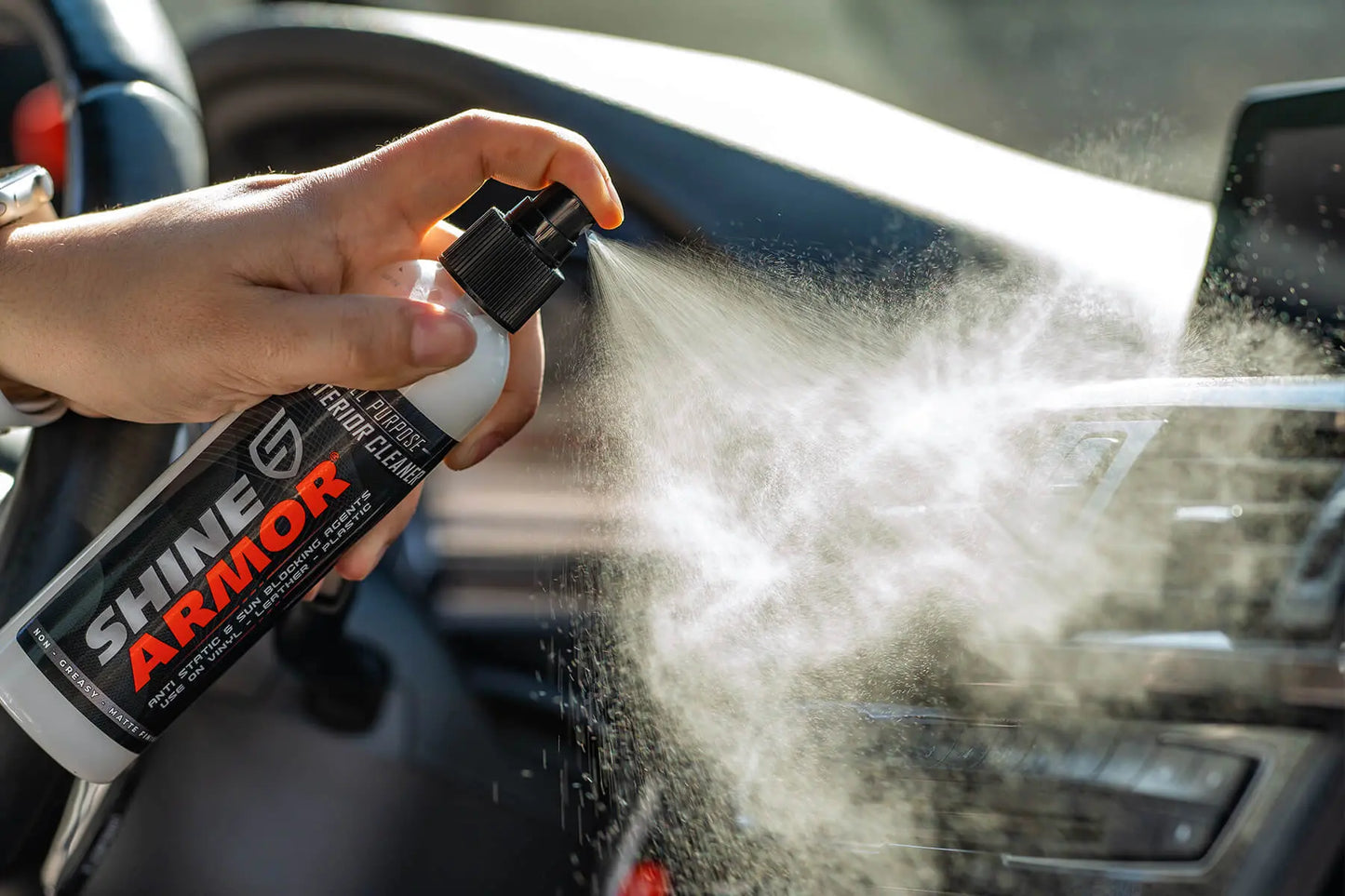 Person spraying Shine Armor Interior Cleaner to the dashboard of a car.