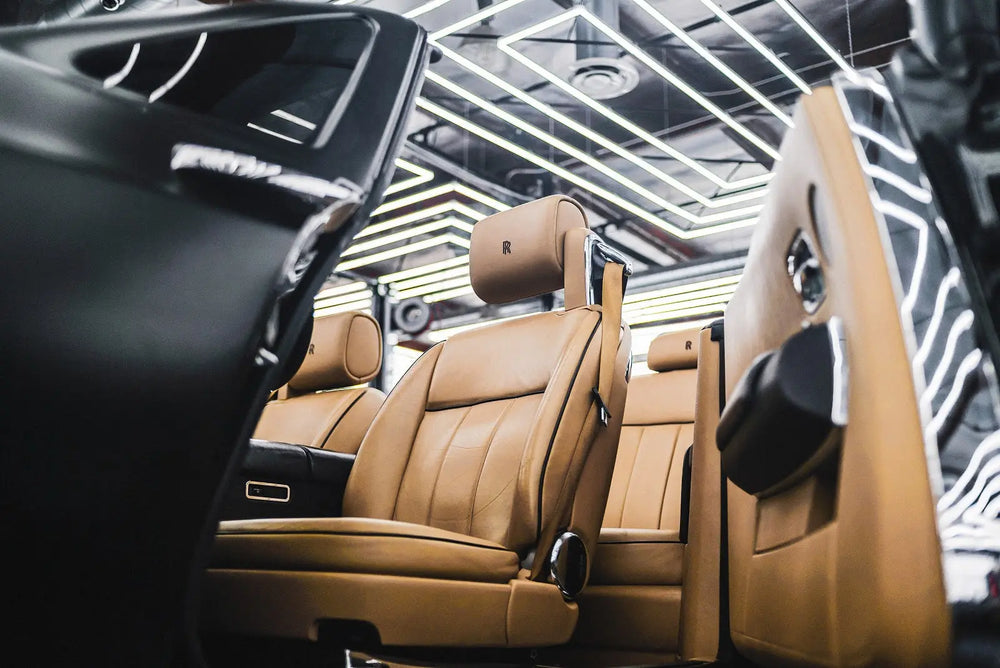 
              Brown leather car seats being installed into a car in a factory.