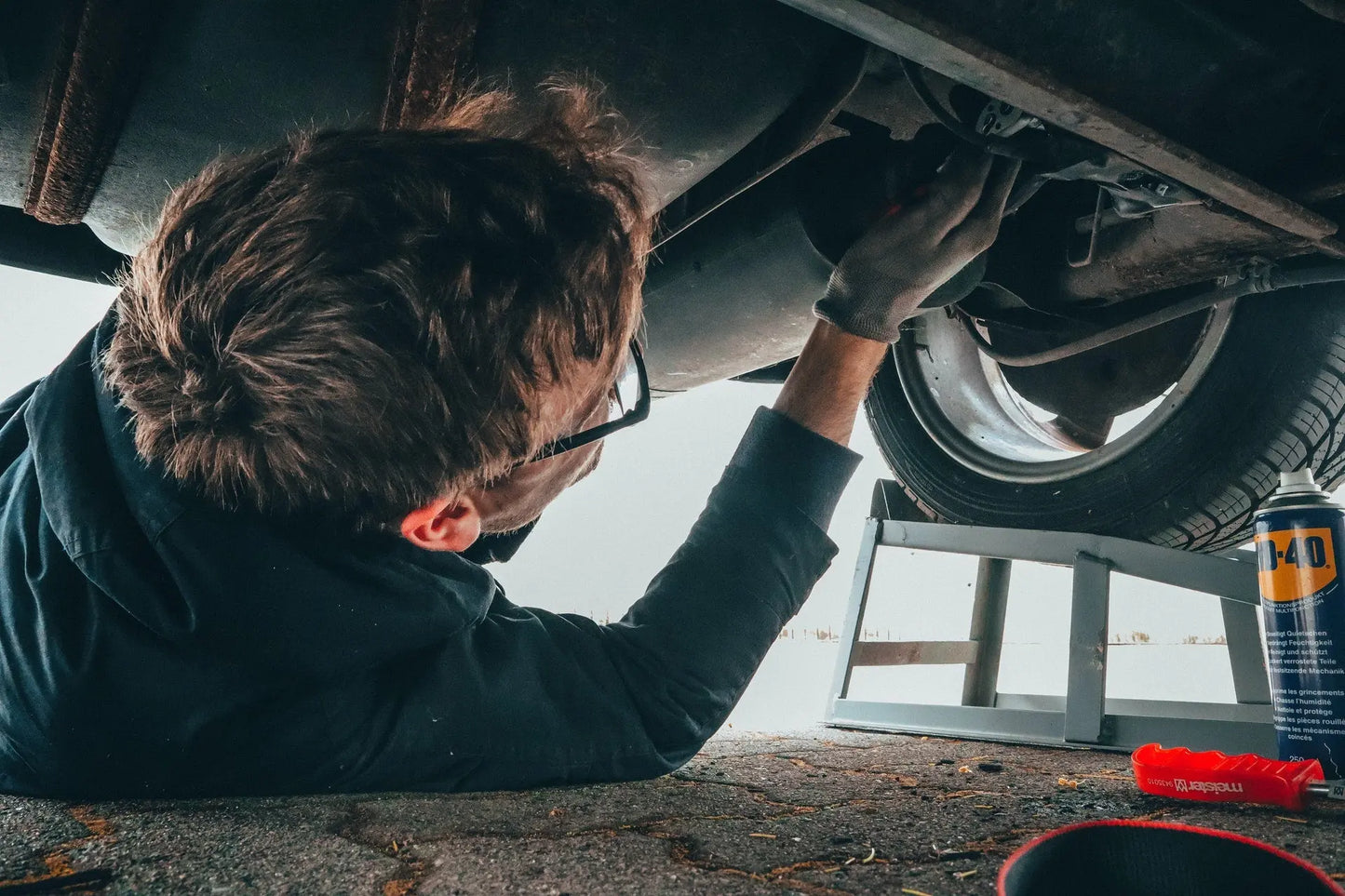 
              Man working underneath a car to change the oil.