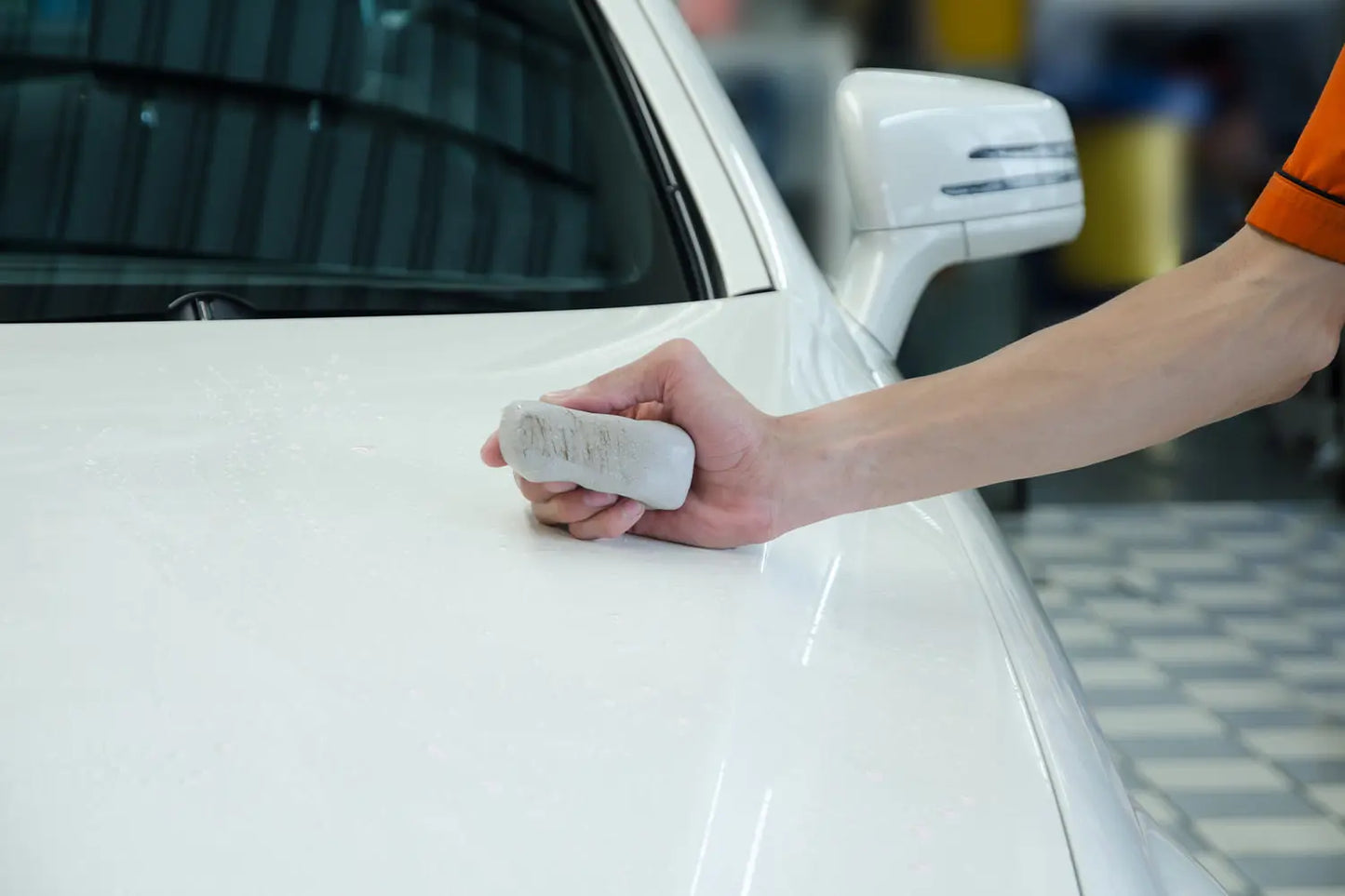 
              Man holding a clay bar on a white car