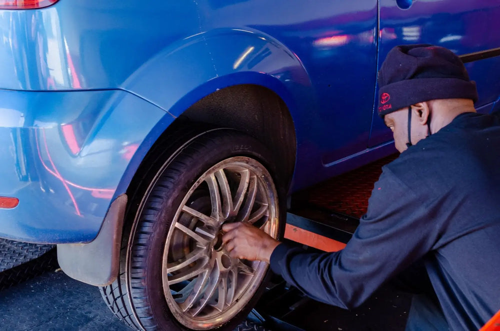 
              Man removing lugnuts from a gold rim on a blue car.
